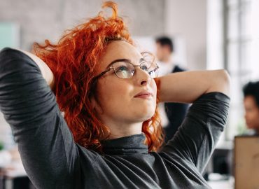 Mujer joven satisfecha con su trabajo tomandose un momento para pensar