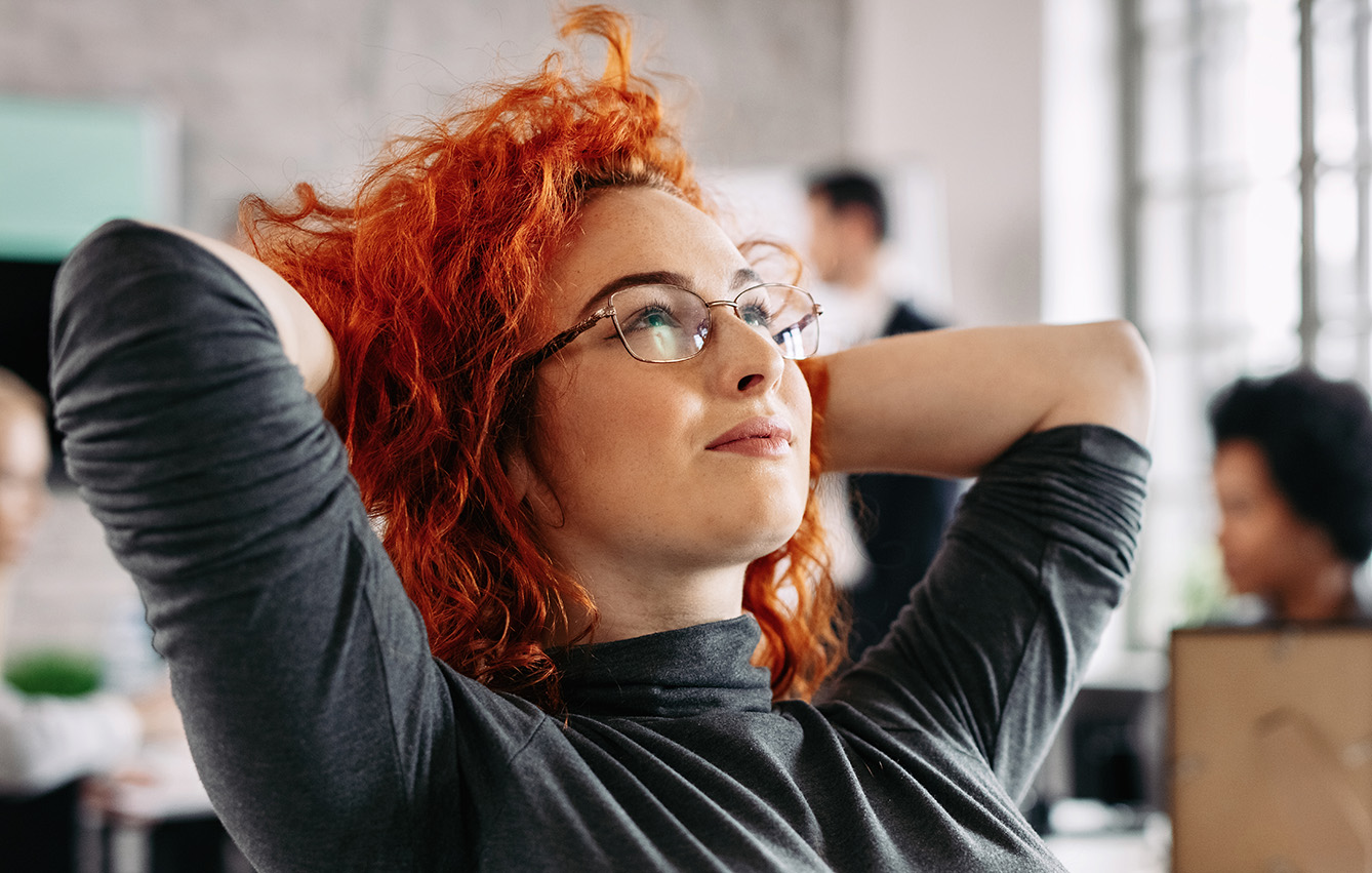 Mujer joven satisfecha con su trabajo tomandose un momento para pensar