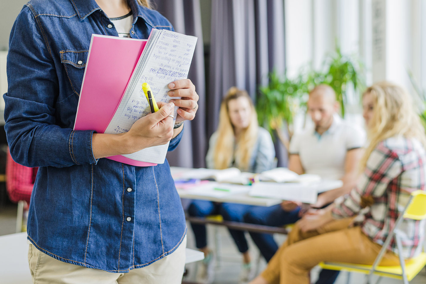Primerplano de mujer joven con cuaderno en los brazos en una clase de preparación para oposiciones