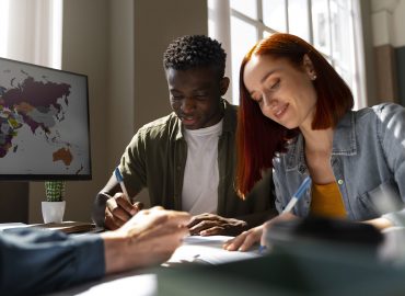 Hombre joven de color firmando un documento junto a una mujer joven caucasica en una oficina