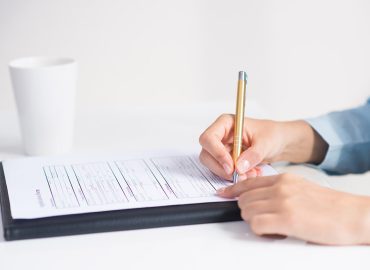 Manos de mujer rellenando un formulario de matriculación a mano